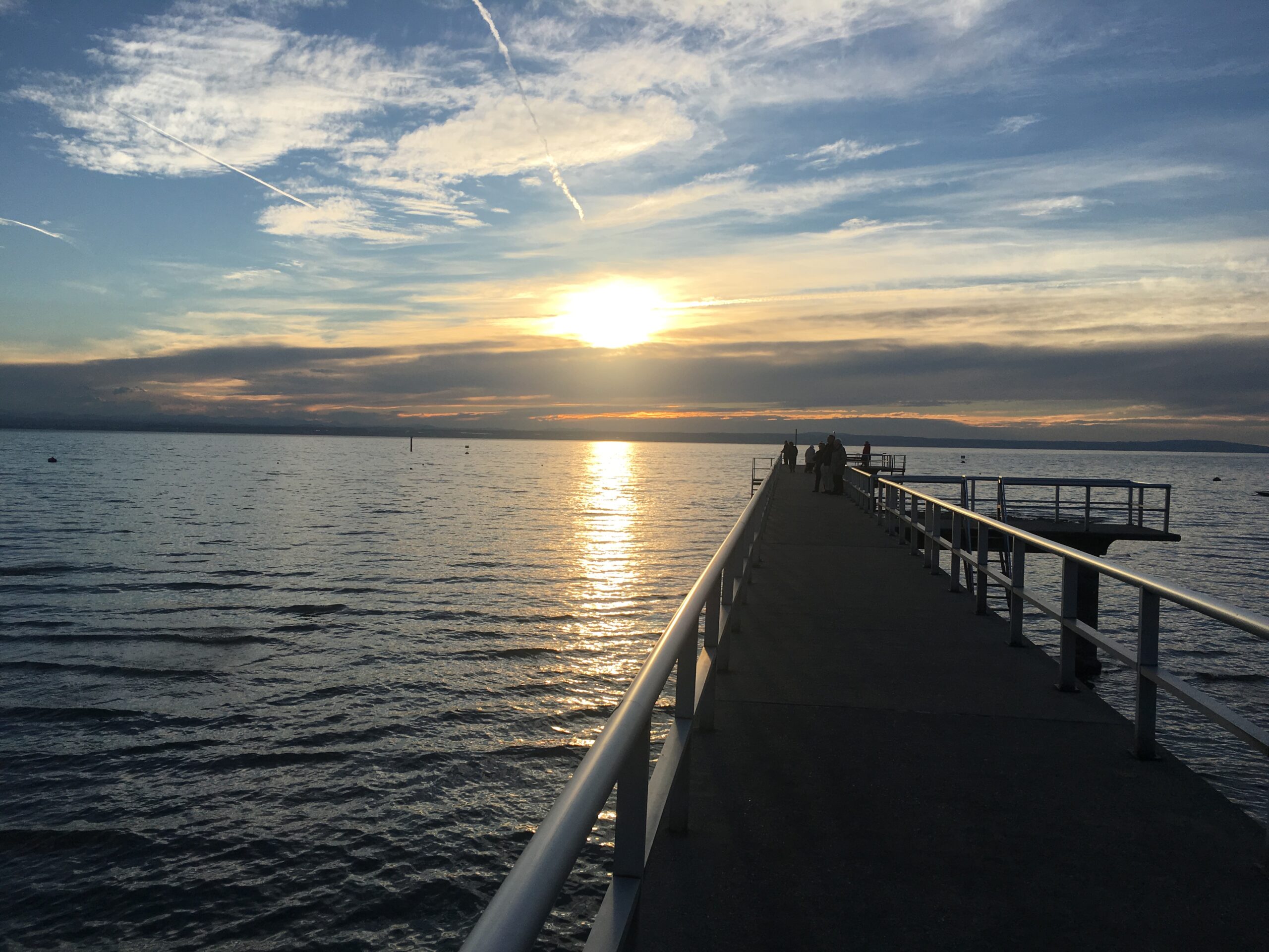 Bild von einem Steg im See, der in einen Sonnenaufgang führt