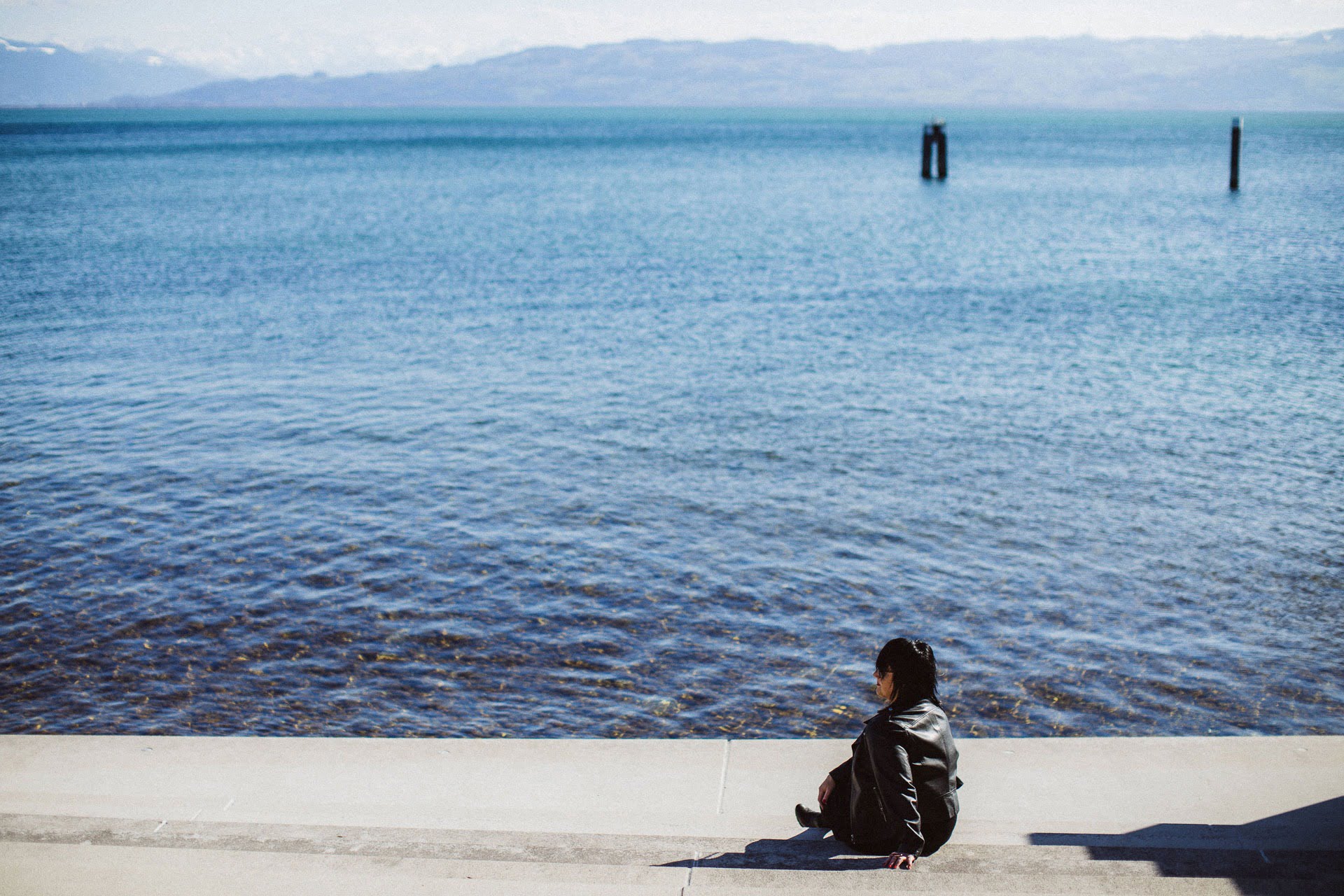 Frau sitzt am Bodensee und hat sich vom Gedankenkarussell befreit.