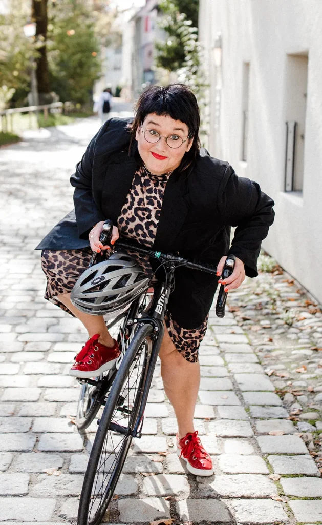 Sabine schaut frontal in die Kamera und steigt auf ihr Rennrad um loszufahren