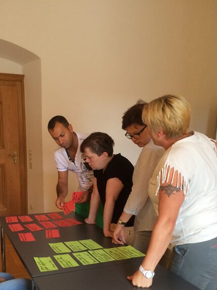 In meine Coachings für Unternehmen werden Ergebnisse gemeinsam diskutiert. Eine Gruppe sieht sich Notizkarten an und diskutiert darüber.