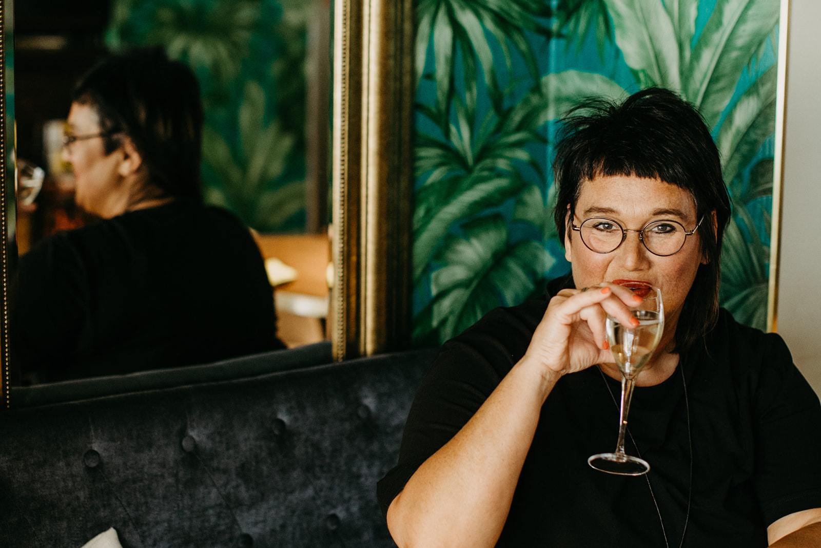 Sabine, Coach für Frauen ab 50, trinkt in einem Cafe ein Glas Sekt. 