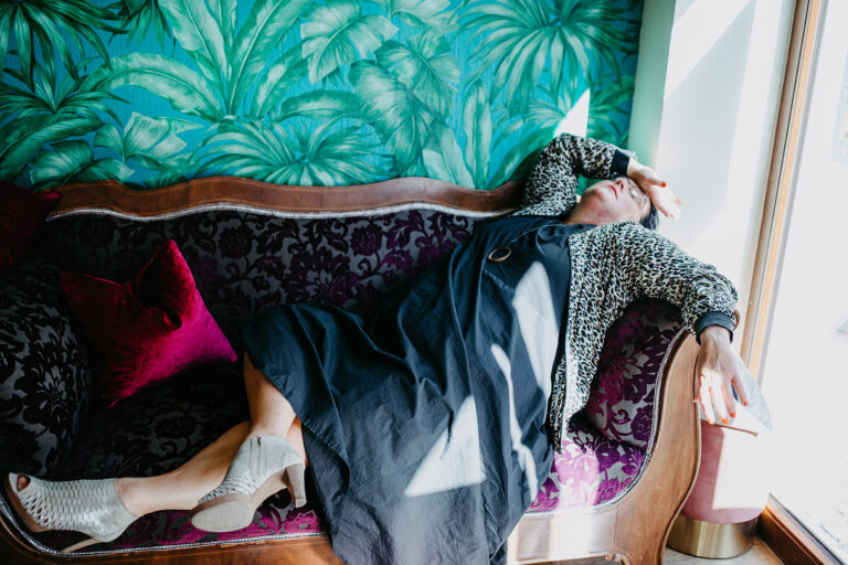 Eine Frau liegt erschöpft vor lauter Helfen auf einem Sofa