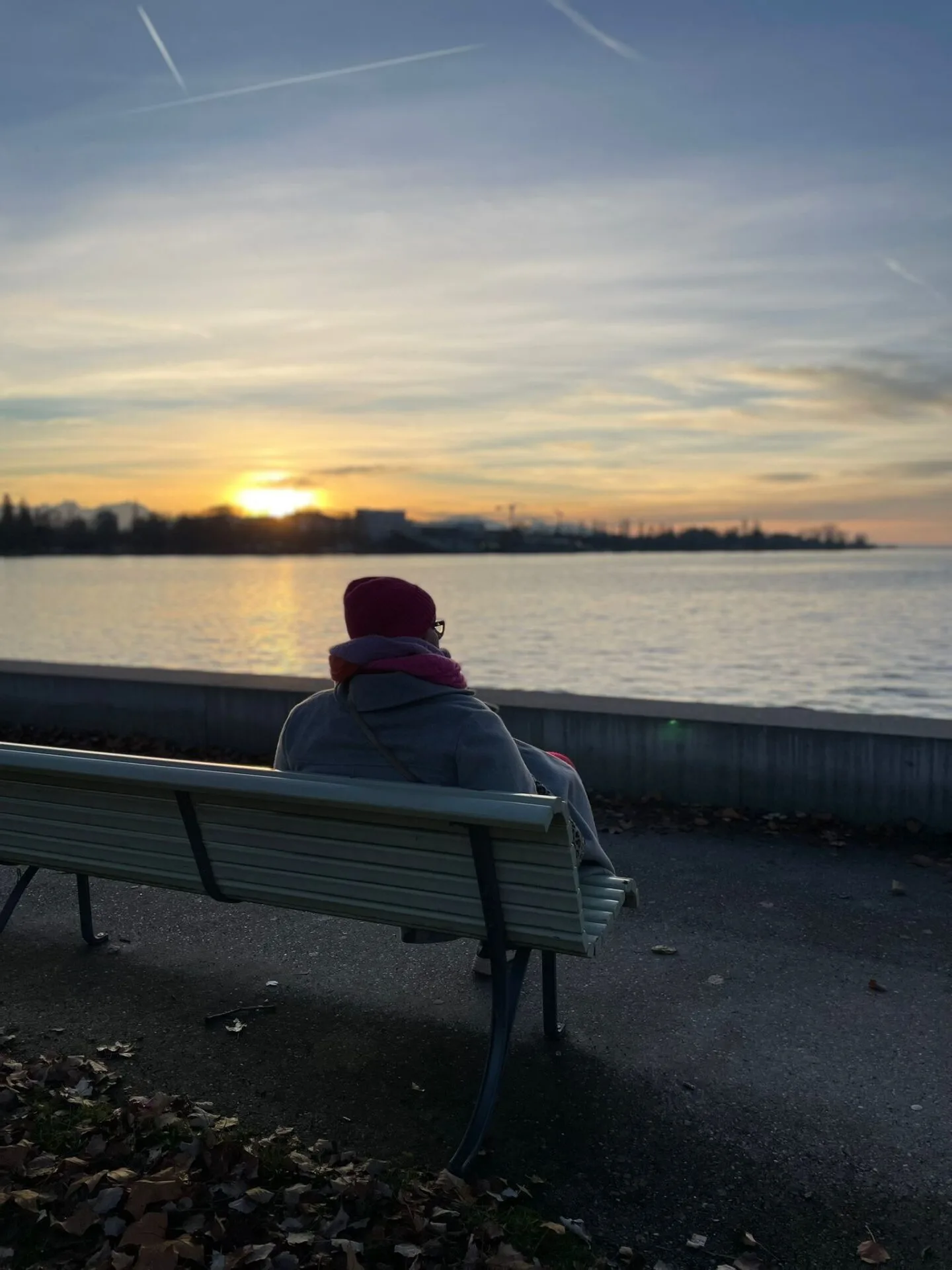 Führungsfrau Sabine Jung-Bass sitzt im Abendrot an einem See und reflektiert das Jahr